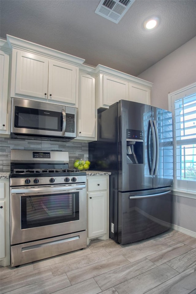 279 Capetown, Conroe, TX 77356 - kitchen featuring appliances with stainless steel finishes, decorative backsplash, white cabinets, a textured ceiling, and recessed lighting