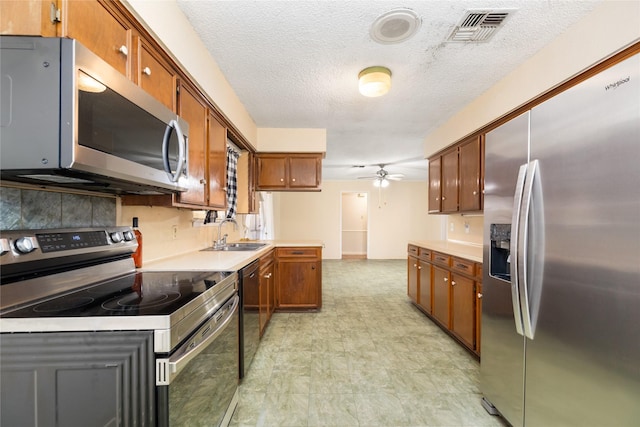 kitchen with a ceiling fan, brown cabinets, stainless steel appliances, light countertops, and visible vents