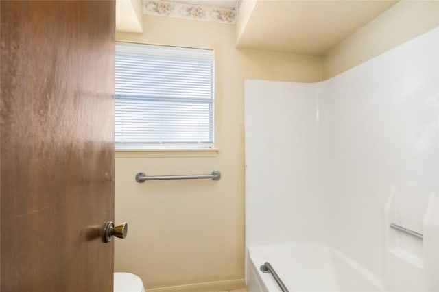 bathroom with a tub to relax in, baseboards, toilet, and a shower