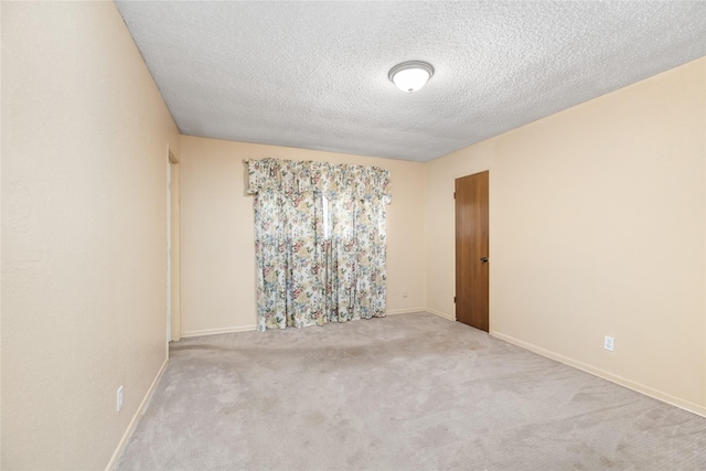 unfurnished room with carpet floors, a textured ceiling, and baseboards