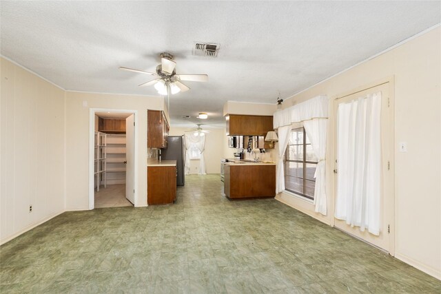 unfurnished living room featuring light floors, visible vents, ceiling fan, and crown molding