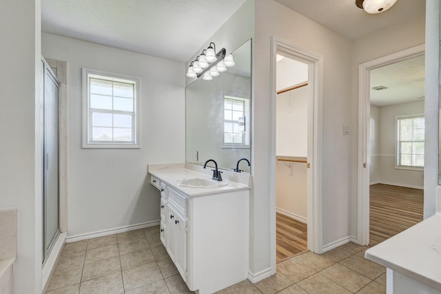27 Westwood Dr W, Trinity, TX 75862 - bathroom featuring tile patterned floors, vanity, a stall shower, a walk in closet, and baseboards