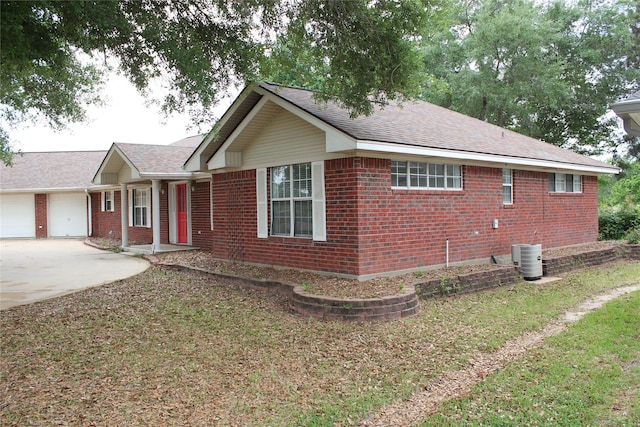 27 Westwood Dr W, Trinity, TX 75862 - view of front facade with brick siding, driveway, an attached garage, central AC, and roof with shingles