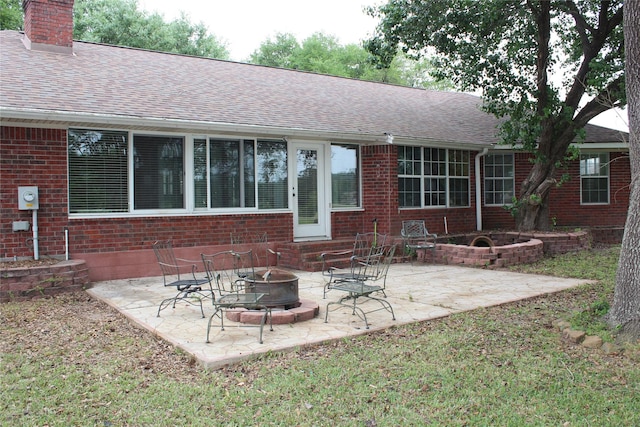 27 Westwood Dr W, Trinity, TX 75862 - back of house featuring a fire pit, brick siding, a shingled roof, and a chimney