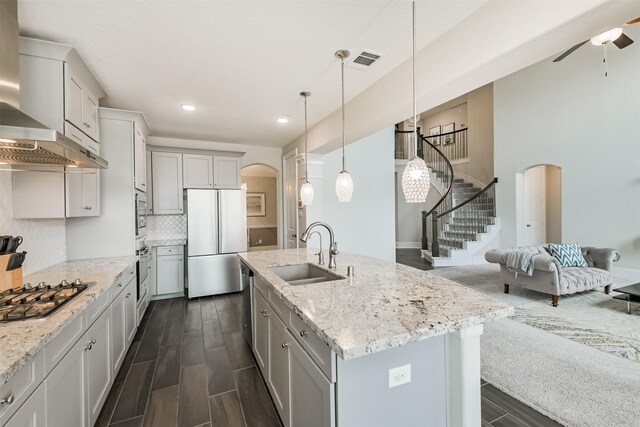 12107 Allington Cove Ln, Humble, TX 77346 - kitchen with visible vents, a sink, arched walkways, wall chimney exhaust hood, and appliances with stainless steel finishes