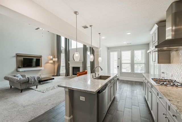 12107 Allington Cove Ln, Humble, TX 77346 - kitchen with stainless steel appliances, visible vents, a sink, wall chimney exhaust hood, and a glass covered fireplace