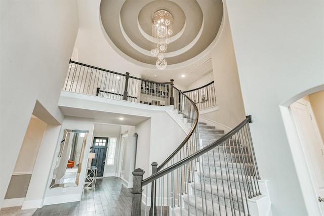 12107 Allington Cove Ln, Humble, TX 77346 - staircase with arched walkways, a towering ceiling, a raised ceiling, baseboards, and a notable chandelier