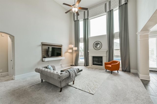 12107 Allington Cove Ln, Humble, TX 77346 - living area featuring a ceiling fan, arched walkways, baseboards, a glass covered fireplace, and high vaulted ceiling