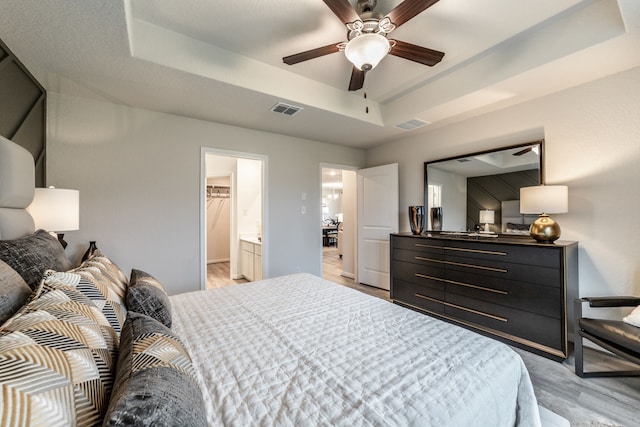 1200 Haverford Ln, Dayton, TX 77535 - bedroom with a ceiling fan, a tray ceiling, visible vents, and light wood-style floors