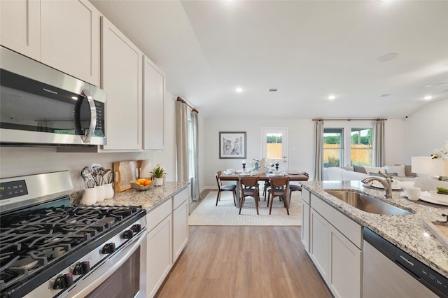 804 Timmons Ln, Dayton, TX 77535 - kitchen featuring a sink, open floor plan, white cabinetry, light wood-style floors, and appliances with stainless steel finishes