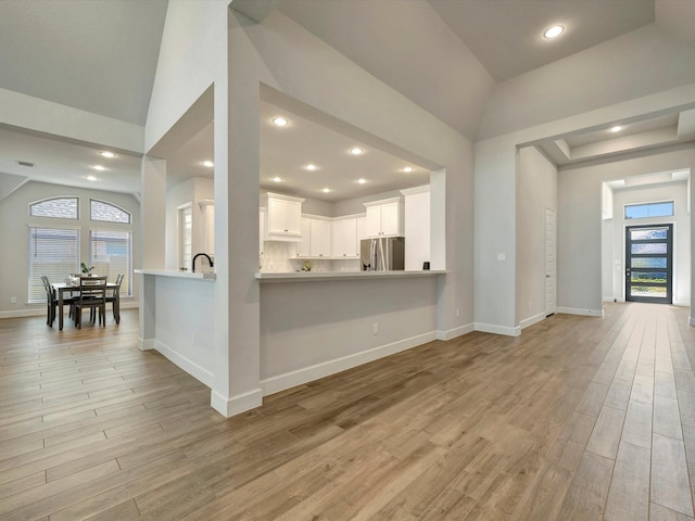 interior space featuring stainless steel refrigerator with ice dispenser, a healthy amount of sunlight, and lofted ceiling