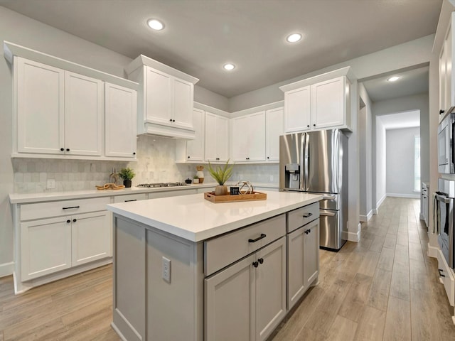 kitchen featuring light countertops, backsplash, stainless steel appliances, and white cabinetry