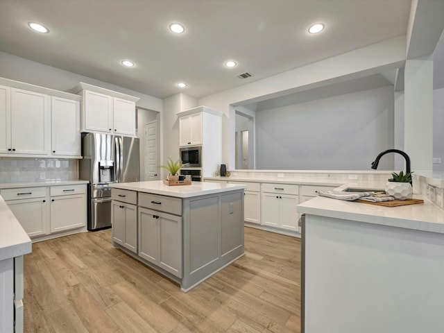 kitchen featuring stainless steel fridge, light countertops, light wood-style floors, and backsplash