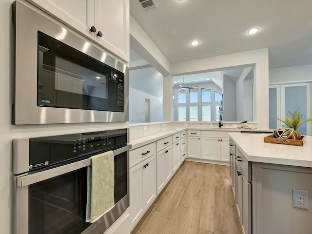 kitchen with ceiling fan, light countertops, stainless steel appliances, white cabinetry, and light wood-type flooring