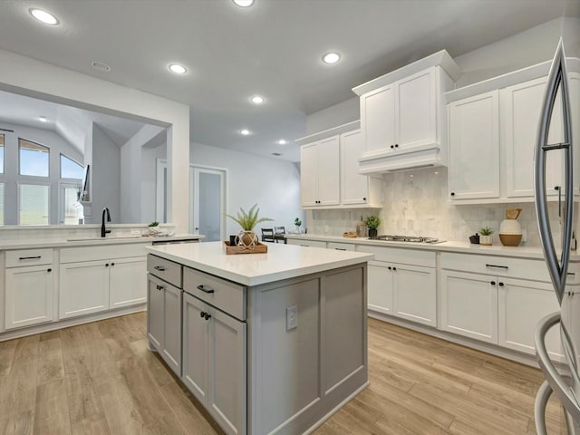kitchen featuring appliances with stainless steel finishes, a sink, light countertops, gray cabinets, and decorative backsplash