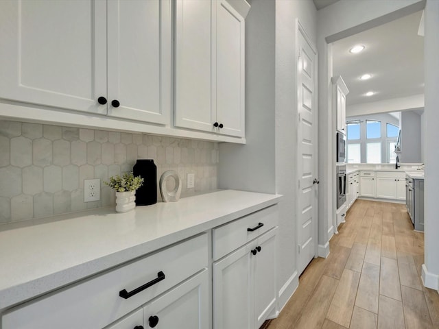 bar with appliances with stainless steel finishes, tasteful backsplash, light wood-type flooring, baseboards, and recessed lighting