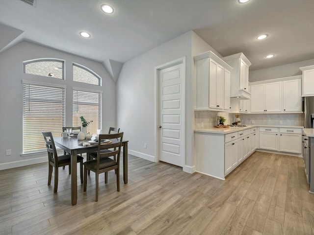 dining area with light wood-style floors, baseboards, and lofted ceiling