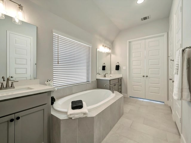 full bath with a sink, two vanities, a bath, and visible vents