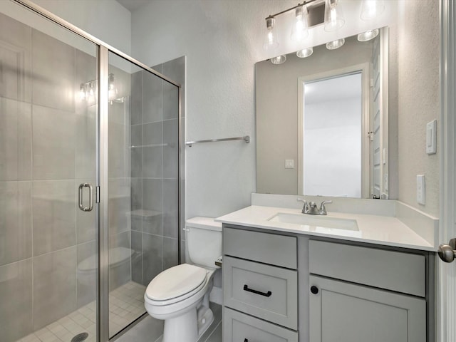 full bath featuring vanity, a textured wall, a stall shower, and toilet