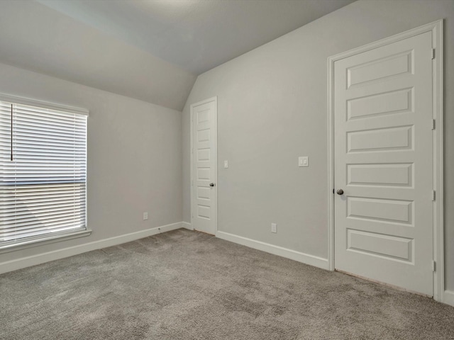 unfurnished room featuring carpet flooring, baseboards, and vaulted ceiling