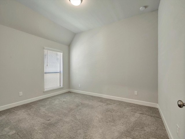 carpeted empty room with baseboards and vaulted ceiling