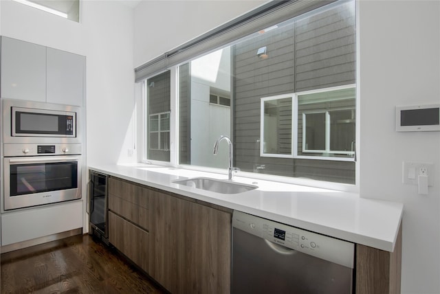 kitchen featuring a sink, dark wood-style flooring, modern cabinets, beverage cooler, and appliances with stainless steel finishes