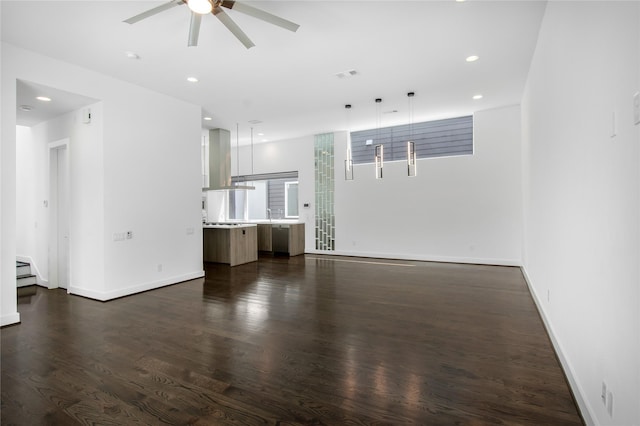 unfurnished living room featuring dark wood-style floors, a ceiling fan, baseboards, visible vents, and recessed lighting