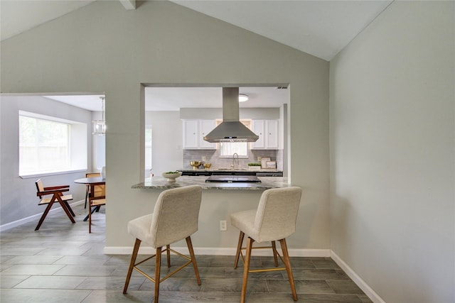 17434 Jolly Boat Dr, Crosby, TX 77532 - kitchen featuring island exhaust hood, a sink, a breakfast bar area, white cabinetry, and backsplash