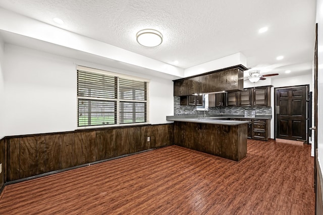 kitchen featuring a peninsula, a textured ceiling, dark brown cabinets, backsplash, and ceiling fan