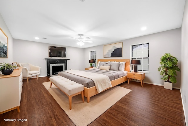 bedroom featuring a ceiling fan, a fireplace, baseboards, dark wood-type flooring, and recessed lighting