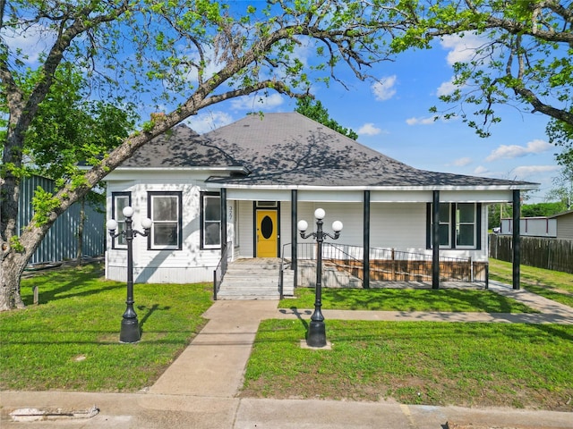 view of front of home with a porch, fence, and a front yard