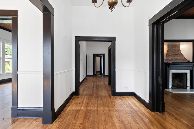 hall with a notable chandelier, a wainscoted wall, and wood finished floors