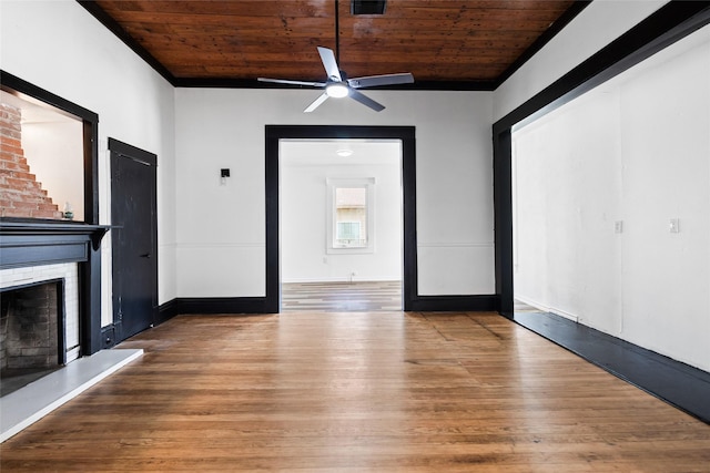 unfurnished living room with wood finished floors, baseboards, wood ceiling, a brick fireplace, and ceiling fan