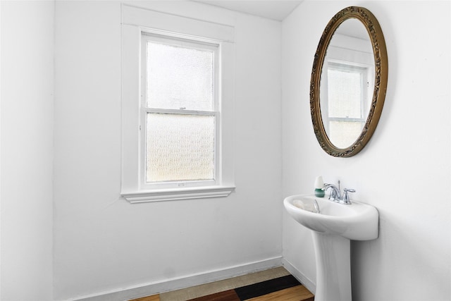bathroom featuring wood finished floors, baseboards, and a healthy amount of sunlight
