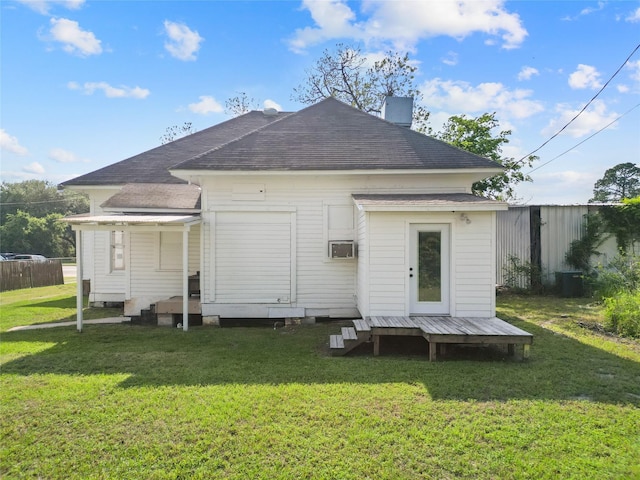 back of house with roof with shingles and a yard