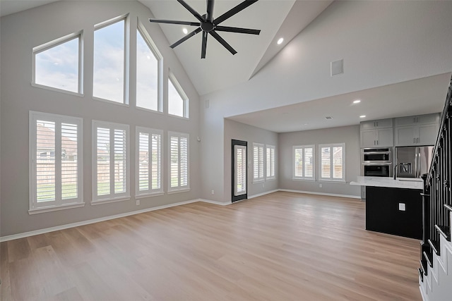 2006 Deer Vly, Missouri City, TX 77459 - unfurnished living room featuring light wood finished floors, high vaulted ceiling, a ceiling fan, recessed lighting, and baseboards