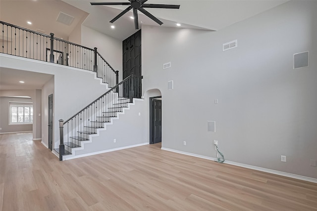 2006 Deer Vly, Missouri City, TX 77459 - unfurnished living room featuring visible vents, a ceiling fan, a towering ceiling, arched walkways, and light wood-style flooring
