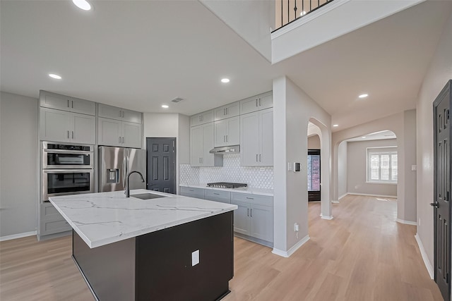 2006 Deer Vly, Missouri City, TX 77459 - kitchen with backsplash, appliances with stainless steel finishes, arched walkways, a sink, and gray cabinetry