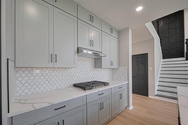 2006 Deer Vly, Missouri City, TX 77459 - kitchen with under cabinet range hood, gray cabinetry, stainless steel gas stovetop, and light wood-type flooring
