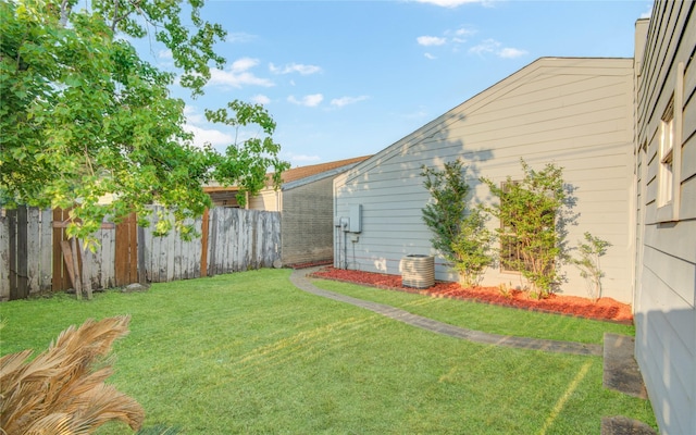 view of yard featuring fence and central AC