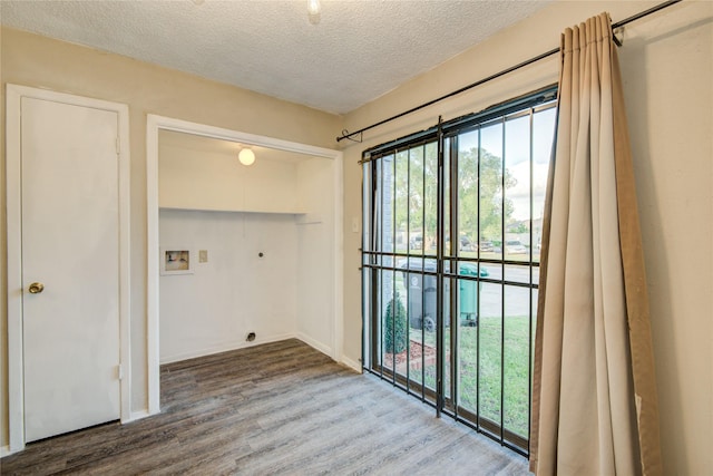 washroom with hookup for an electric dryer, hookup for a washing machine, baseboards, a textured ceiling, and wood finished floors
