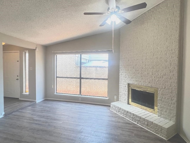 unfurnished living room featuring a fireplace, lofted ceiling, a ceiling fan, a textured ceiling, and wood finished floors
