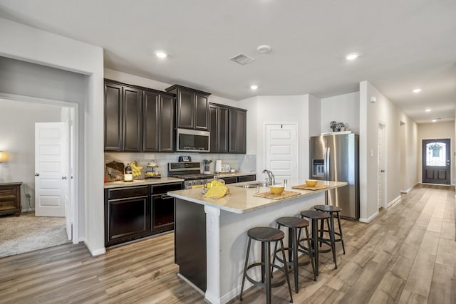 kitchen with light wood finished floors, stainless steel appliances, visible vents, and a sink