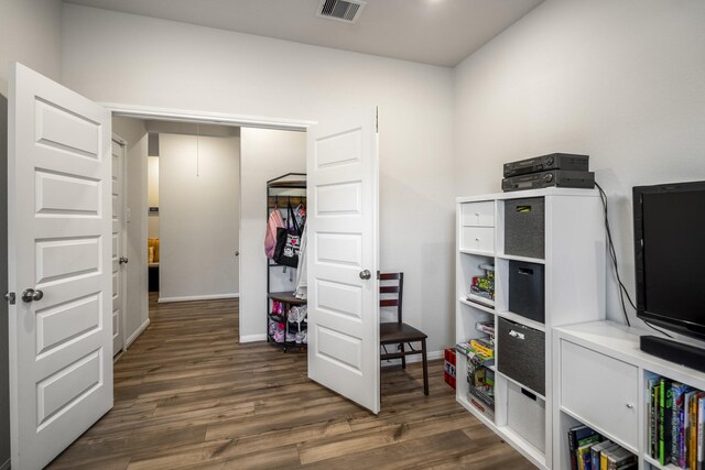 interior space featuring attic access, baseboards, wood finished floors, and visible vents