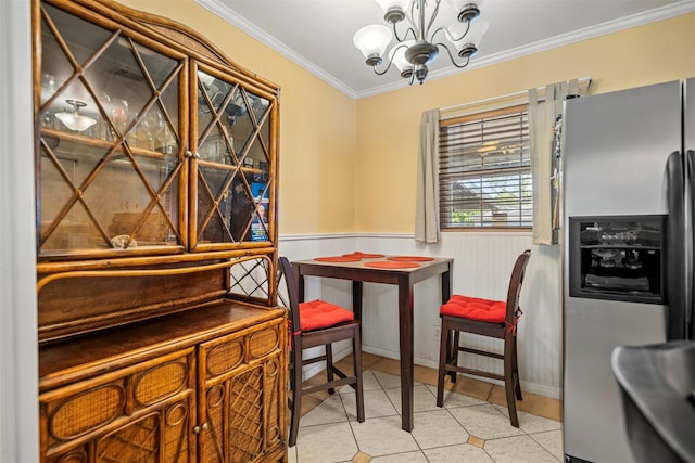 dining space featuring wainscoting, an inviting chandelier, ornamental molding, and light tile patterned floors