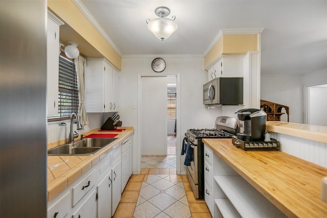 kitchen with crown molding, a sink, tile countertops, light tile patterned floors, and stainless steel appliances