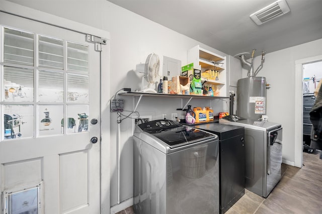 washroom featuring washer and clothes dryer, water heater, visible vents, baseboards, and laundry area