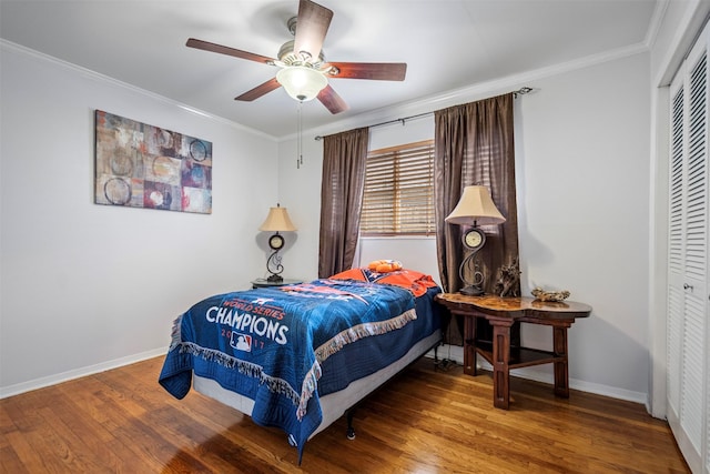 bedroom with wood finished floors, a closet, baseboards, and ornamental molding