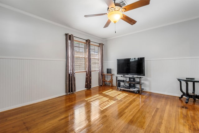 living room featuring wood finished floors, visible vents, ceiling fan, and wainscoting