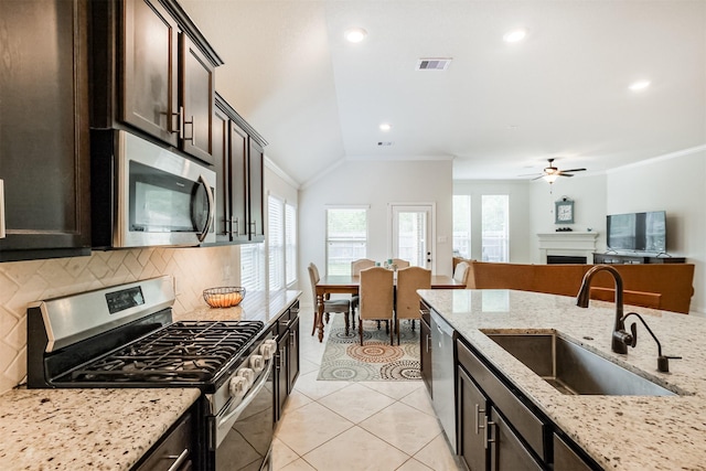 kitchen with visible vents, a sink, dark brown cabinetry, a fireplace, and appliances with stainless steel finishes